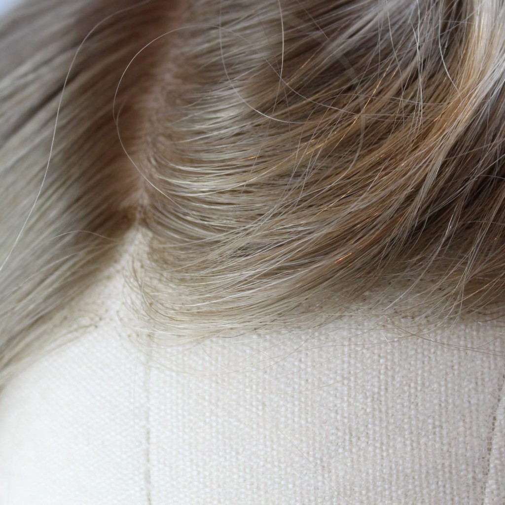 Close-up of the lace front and parting of a light blonde wig made in the Enhanced Hair Studio